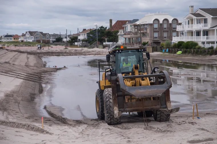 A construction vehicle purposed for moving dredging pipes backs into a pool of water at the beach in Margate.