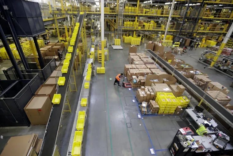 Employees work at the Amazon Fulfillment center in Robbinsville Township, N.J.  The company is boosting its minimum wage for all U.S. workers to $15 per hour starting next month.
