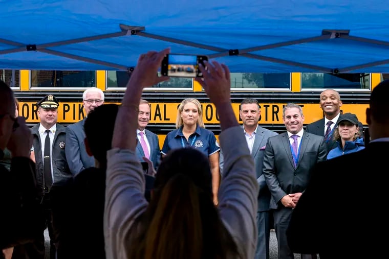 School bus driver Stacey Kendall (center) poses with Camden County law enforcement, school, health, elected and public officials following a news conference at Triton Regional High School in Runnemede, Tuesday, Sept. 26, 2023 to announce the county is providing naloxone kits to school bus drivers.