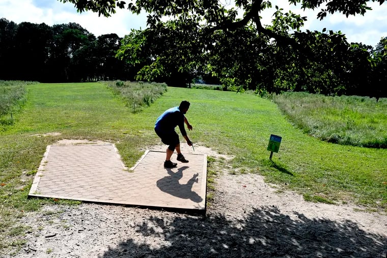 Golfer Kevin Cook “drives” his disc from the tee pad down the fairway at Stafford Woods Disc Golf Course in Voorhees, N.J., Saturday.