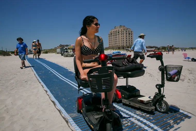 Bernadette Scarduzio rides her scooter to the end of the newly installed beach mat that she advocated for, in Brigantine, New Jersey, Tuesday, July 10, 2018.