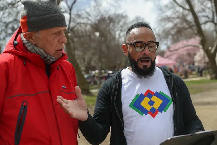 Eduardo Luna of Philadelphia Heritage Chorale sings with Jerry Forman (left) as part of "Rehearsing Philadelphia" in Clark Park in West Philadelphia on Saturday. "Rehearsing Philadelphia" is a public project that explores how the city can come together through musical rehearsal.