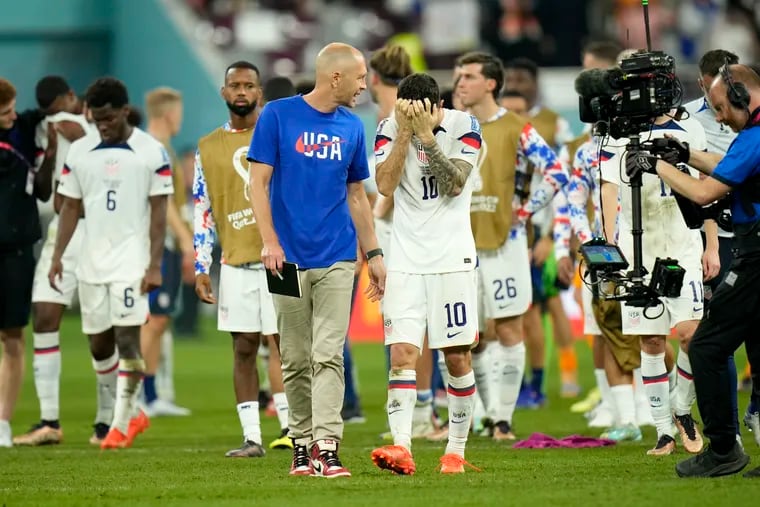 U.S. men's soccer team manager Gregg Berhalter (left) walks with a crestfallen Christian Pulisic (right) after the game.