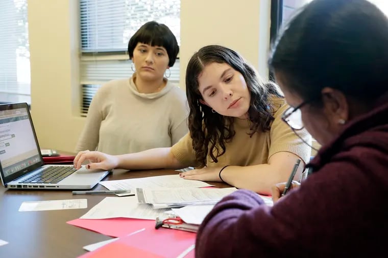 Quaker Voluntary Service fellow Sarah Bluett (left) and community engagement specialist Joanna Rosenhein (middle) help a client review their health coverage options at The Friends Center in Philadelphia in November.
