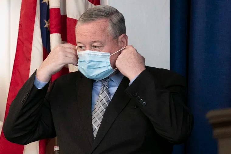 Mayor Jim Kenney puts on his mask during a press conference. Kenney announced that Philadelphia would mandate masks starting at midnight on Aug. 12, 2021.
