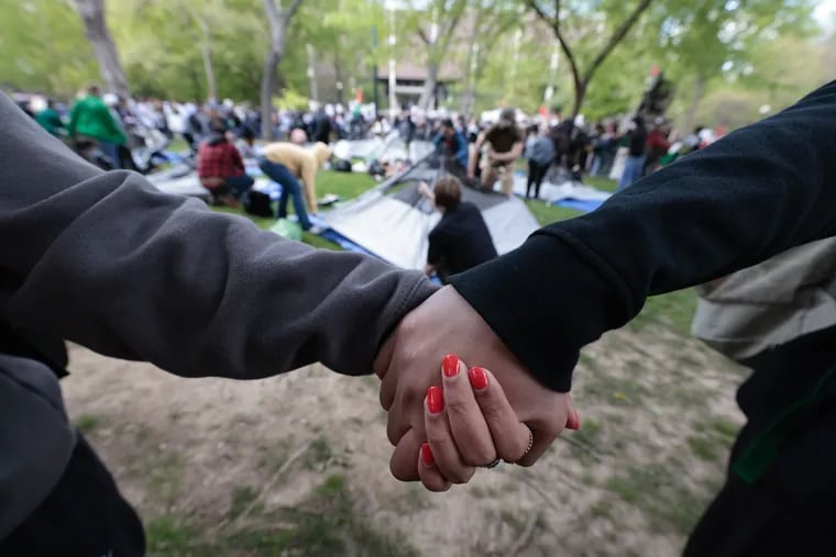 People join hands in a circle as tents are erected on Penn’s campus as part of a pro-Palestinian protest on Thursday.