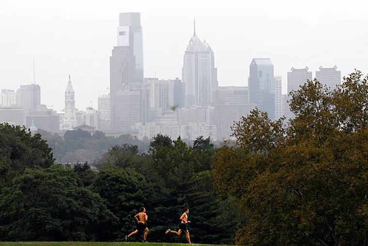 Joggers run on the Belmont Plateau in Fairmount Park with cloudy Center City Philadelphia in the background on Tuesday, September 18, 2012.  (Yong Kim / Staff Photographer)