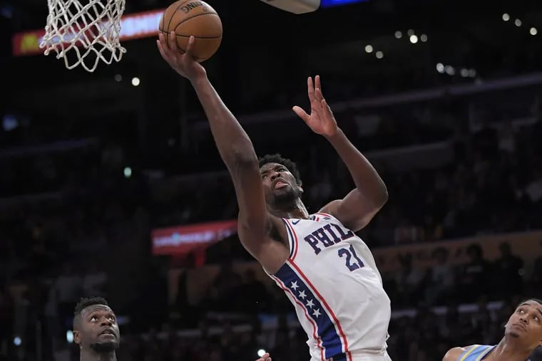Sixers center Joel Embiid, center, shoots as Lakers forward Julius Randle, left, and guard Jordan Clarkson defend during the second half on Wednesday.