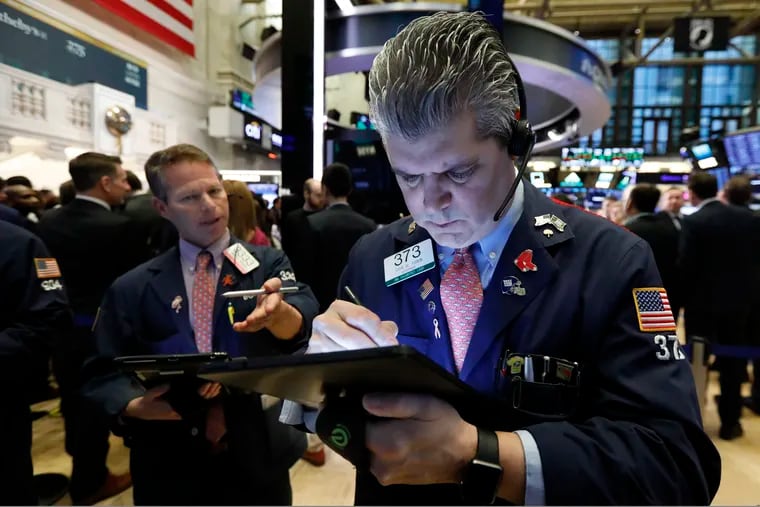 In this March 11, 2019, file photo trader John Panin, right, works on the floor of the New York Stock Exchange.