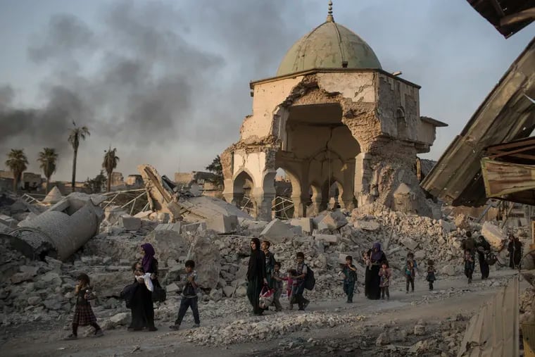 FILE - In this July 4, 2017, file photo, fleeing Iraqi civilians walk past the heavily damaged al-Nuri mosque as Iraqi forces continue their advance against Islamic State militants in Iraq's Old City of Mosul. Iraqi religious leaders have laid the cornerstone to rebuild Mosul's landmark al-Nuri mosque, which was blown up in the battle with Islamic State militants in 2017. (AP Photo/Felipe Dana, File)