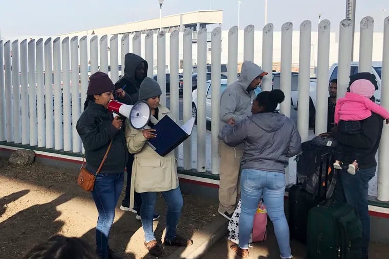 Volunteers call names of people on a waiting list trying to obtain asylum in the United States along the U.S.-Mexico border in Tijuana, Mexico on Nov. 12, 2019. President Donald Trump’s latest immigration crackdown includes proposed changes to application fees.