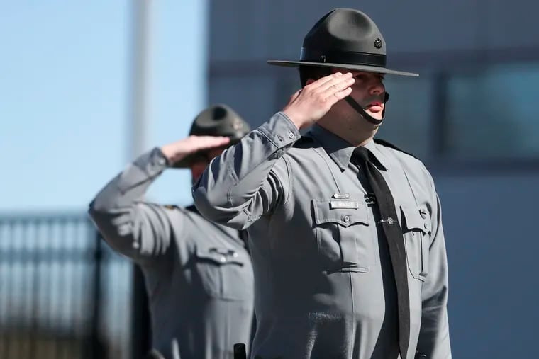 Troopers stand at attention while the state flag is lowered to half mast during a press conference at the Pennsylvania State Police, Troop K Station.