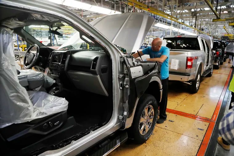 FILE- In this Sept. 27, 2018, file photo a United Auto Workers assemblyman works on a 2018 Ford F-150 truck being assembled at the Ford Rouge assembly plant in Dearborn, Mich. Ford is recalling 327,000 F-Series pickup trucks in North America for a second time to fix problems with engine block heater cables that can cause fires. The recall covers F-150s from 2015 through 2019, as well as Super Duty trucks from 2017 through 2019.