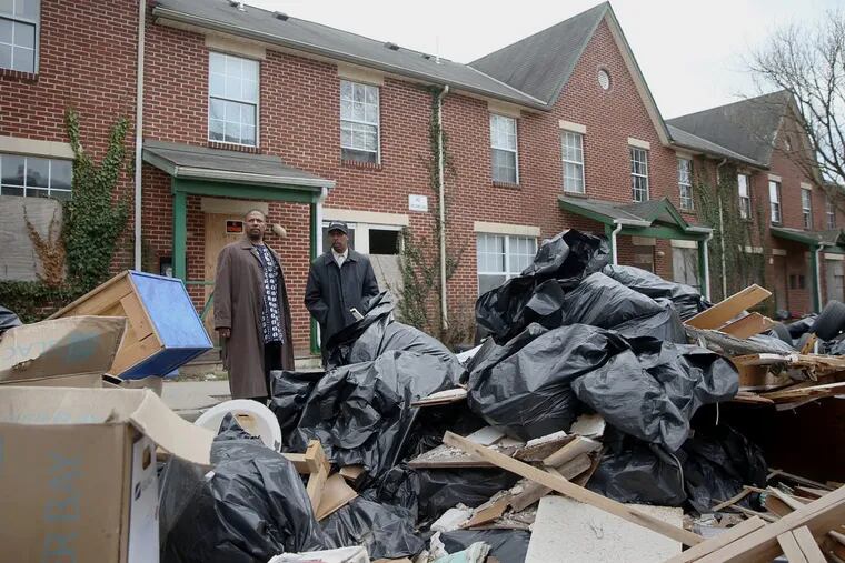Germantown activists  Ted Stones (left) and Keith Q. Schenck navigate the piles of trash at a shuttered affordable housing development built by former Germantown Settlement CEO Emanuel Freeman.