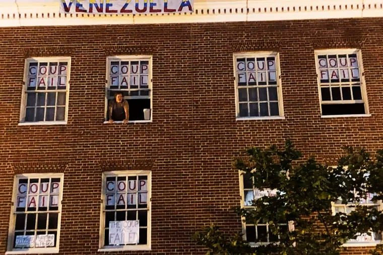 An activist who supports Venezuelan Nicolas Maduro stands by the window of the Venezuelan Embassy in Washington, Monday, May 13, 2019. U.S. authorities have served an eviction notice to activists who have stayed for more than a month inside the embassy and asked them to leave immediately. (AP Photo/Luis Alonso Lugo)