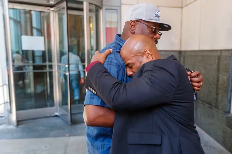 Chester Hollman III, right, buries his head into the chest of his uncle, David Hollman, as the two hugged outside of the Stout Center for Criminal Justice, where Philadelphia Common Pleas Judge Gwendolyn N. Bright dismissed all remaining charges against Hollman on July 30, 2019.