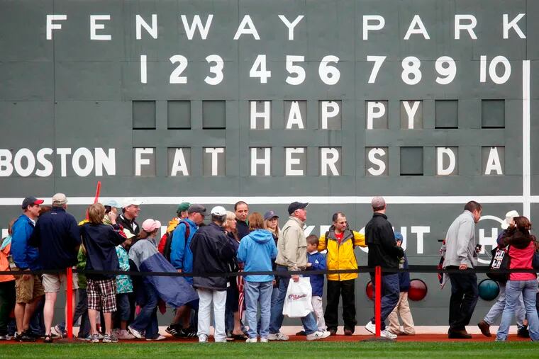 FILE - In this June 21, 2009 file photo, fans tour in front of the scoreboard in Fenway Park in Boston in celebration of Father's Day following a baseball game between the Atlanta Braves and the Boston Red Sox. The U.S. Census Bureau has released a new report showing more than 60% of the 121 million men in the U.S. are fathers. The data in the report released this week of June 15, 2019, comes from 2014 when the bureau for the first time asked both men and women about their fertility histories. The report says just under three-quarters of fathers are married. Almost 13% of dads are divorced and 8% have never been married.  (AP Photo/Michael Dwyer)