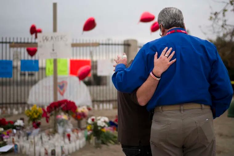 Chaplain Chuck Bender (right) prays with a mourner at a memorial for the shooting victims in San Bernardino, Calif.
