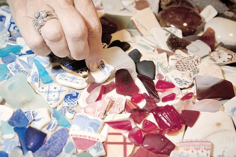 Artist Carol King Hood picks through her sea glass collection that she has displayed on her living room coffee table. Red glass is especially rare. (RON TARVER/Staff Photographer)