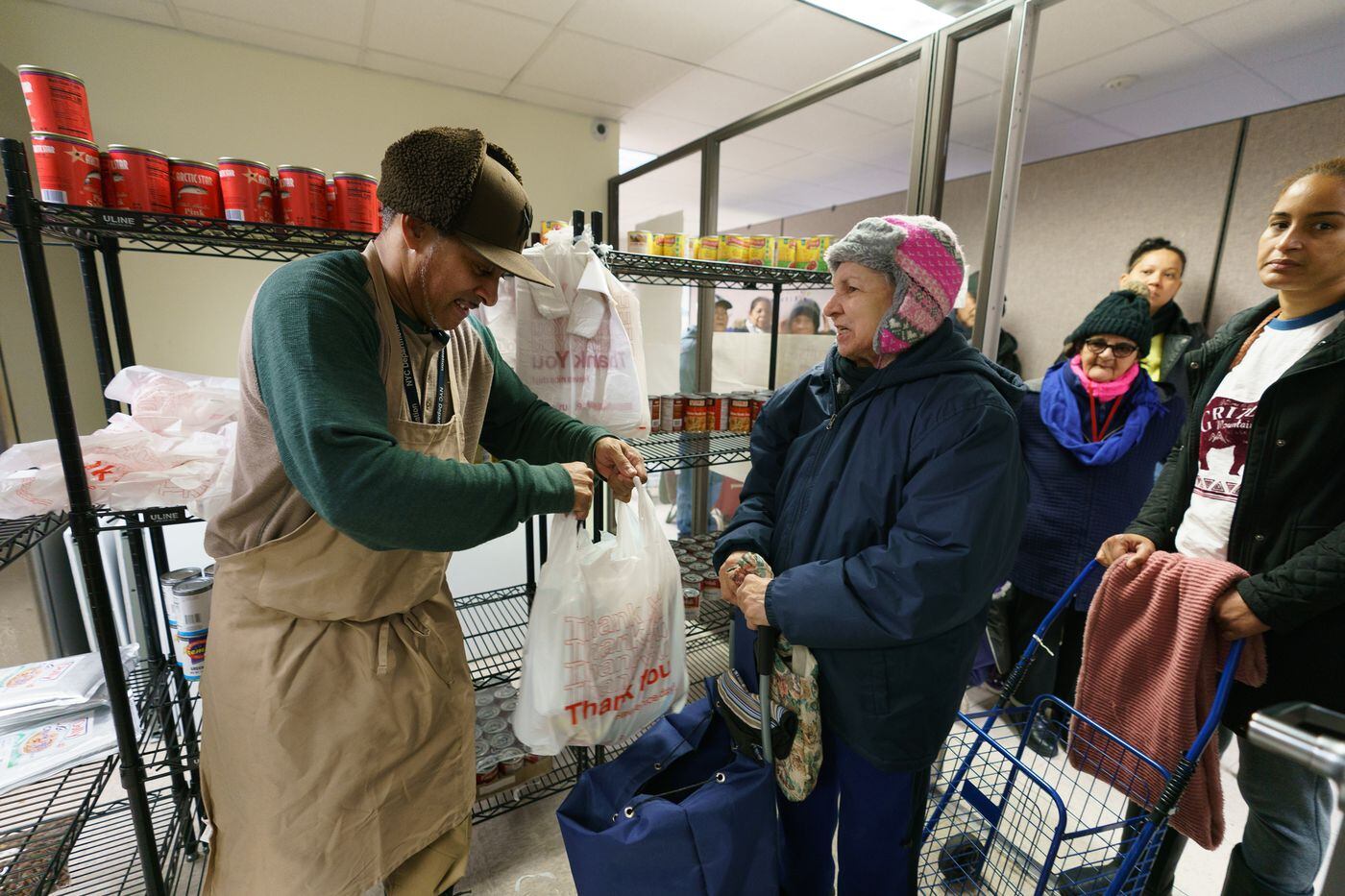 Mario Perez (left), a community service aid at the Nutrition Kitchen, assists Jermania Narr with items from the food pantry at the South Bronx NeON.