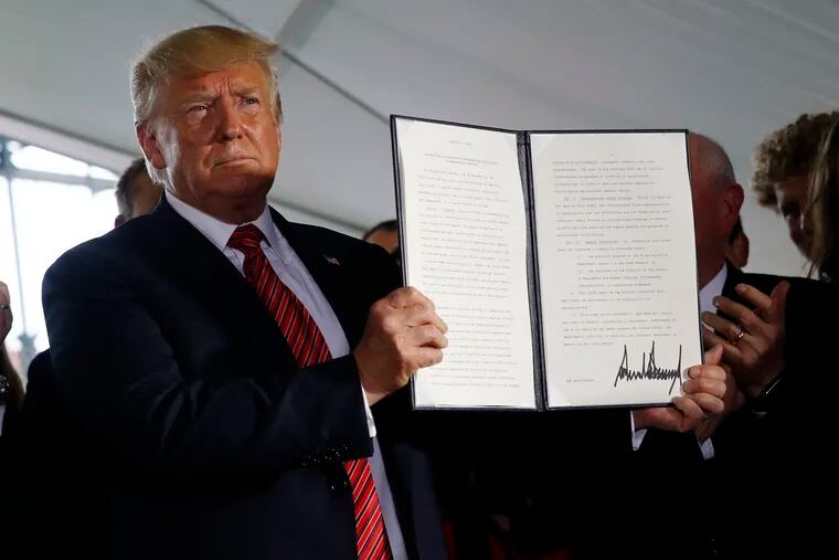 President Donald Trump holds up a signed executive order to streamline the approval process for GMO crops, after speaking at Southwest Iowa Renewable Energy in Council Bluffs, Iowa, Tuesday, June 11, 2019. (AP Photo/Patrick Semansky)