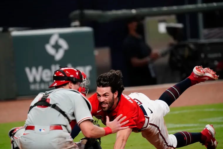 The Braves' Dansby Swanson dives toward home plate and is tagged out by Phillies catcher Andrew Knapp to end the game.