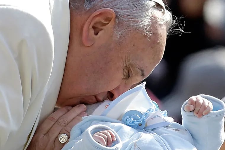 Pope Francis kissing a baby as he arrives for his weekly audience in St. Peter's Square last week. This week marks his second year as pontiff. AP