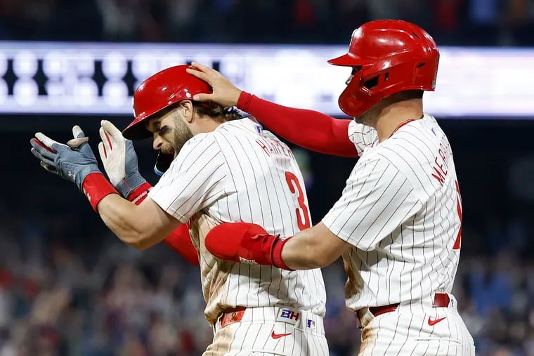 Phillies Bryce Harper celebrates after hitting the game winning sacrifice fly ball in the 10th inning with teammate Whit Merrifield.