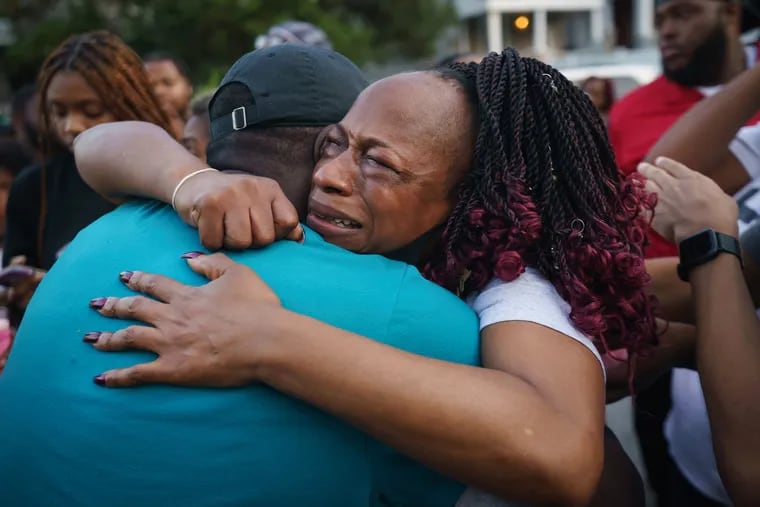 At a candlelight vigil for her son, Florence Reddick is comforted by a family friend on Oct. 3, 2021. Reddick's son, 25-year-old Nassir Day, was working as a security guard when he was fatally shot inside an office building in Philadelphia’s Logan neighborhood.