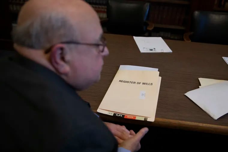 A folder containing labeled "Register of Wills" can be seen behind John Raimondi in the office of Ronald Donatucci in Room 180 of City Hall during a conference on Tuesday, Feb. 19, 2019.
