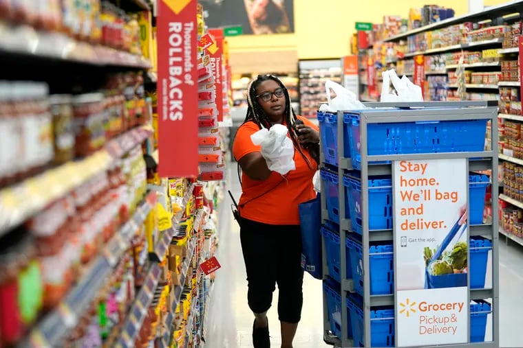FILE - In this Nov. 9, 2018, file photo, Walmart associate Alicia Carter fulfills online grocery orders at a Walmart Supercenter in Houston. Amazon and Walmart on Thursday, April 18, 2019, are kicking off a two-year pilot established by the government to allow low-income shoppers on government food assistance in New York to shop and pay for their groceries online. (AP Photo/David J. Phillip, File)