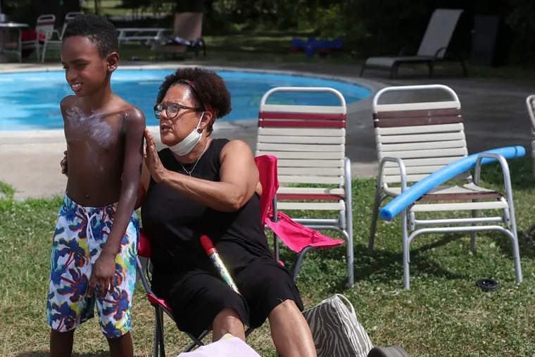 Shelley Tucker applies sun protection on her grandson, Zion Booker, 9, at the Nile Swim Club in Yeadon, on the first day of what was to become quite a hot month.