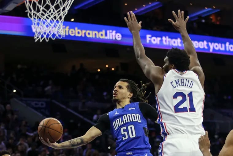 Sixers Joel Embiid tries to block Magics Cole Anthony  during the 2nd quarter at the Wells Fargo Center in Philadelphia, Wednesday,  January 19, 2022.