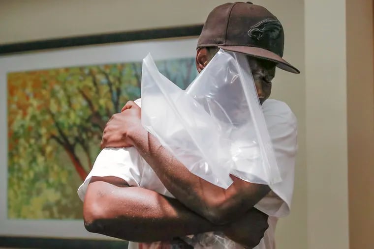 Lionell Dotson hugs the cremated remains of his two sisters, Katricia and Zanetta Dotson,who died in the MOVE bombing, inside the Ivy Hill Crematory in Philadelphia on Wednesday, Aug. 3, 2022.