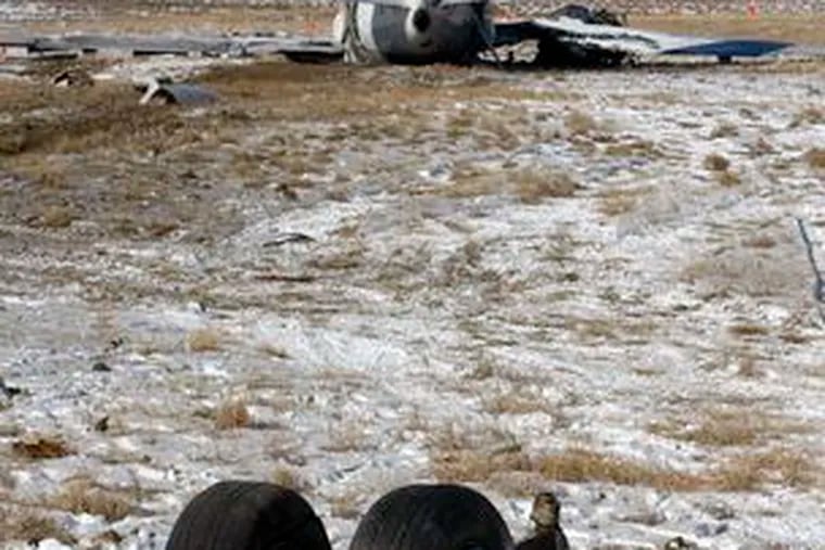Wrecked Continental jet, which crashed Saturday in Denver with 115 aboard, lies yards from landing gear.