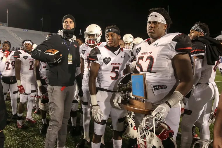 Imhotep head coach Nick Lincoln (left) and his player dejectedly look on as Cathedral Prep celebrates its third consecutive victory over the Panthers in the PIAA Class 4A final.