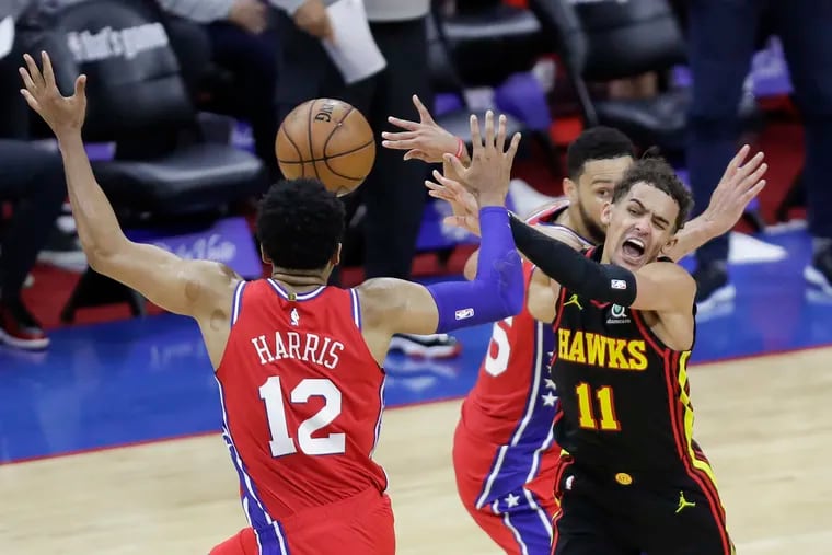 Atlanta Hawks guard Trae Young throws a pass between Sixers forward Tobias Harris and guard Ben Simmons late in the fourth quarter in Game 1.