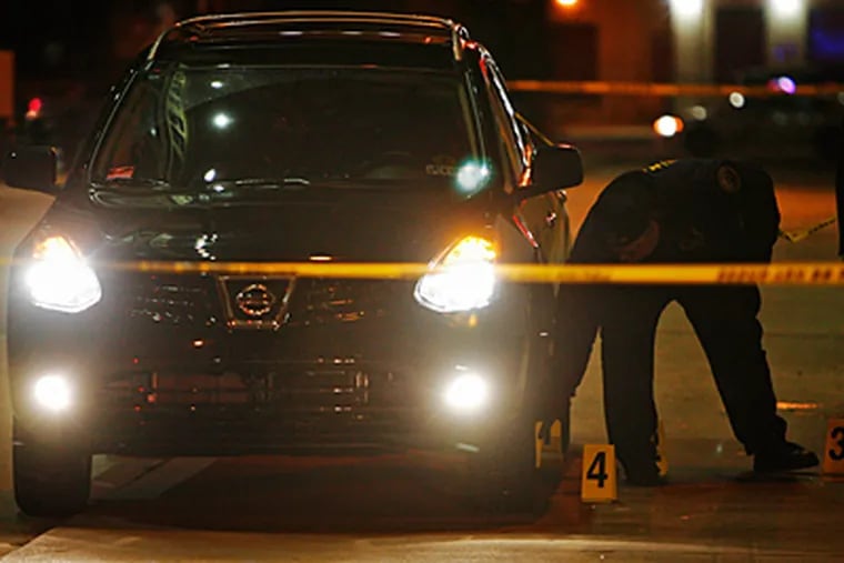 Philadelphia police mark evidence in a fatal shooting early this morning by an off-duty police officer outside the Electric Factory. The officer was in his SUV, pictured, when he says a man tried to rob him, authorities said. (ALEJANDRO A. ALVAREZ / Staff)