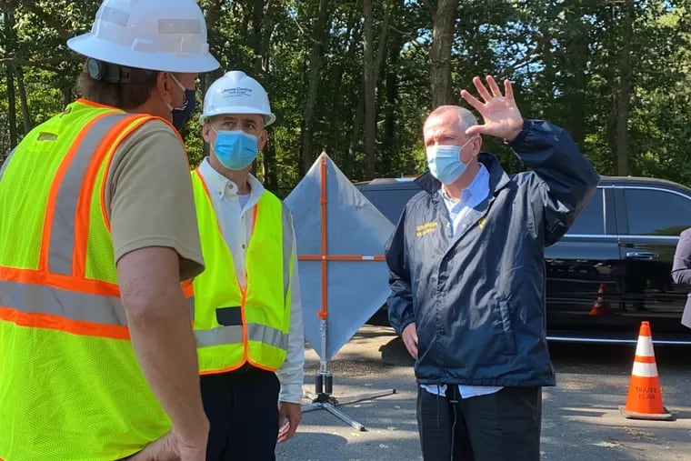 Wearing a mask, New Jersey Gov. Phil Murphy speaks with Jim Fakult, president of Jersey Central Power & Light, in Jackson, Ocean County, on Wednesday in the aftermath of Tropical Storm Isaias.
