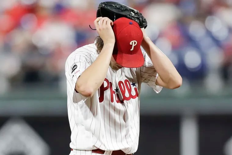 Aaron Nola puts his hands on his head after giving up a second-inning RBI single to Atlanta's Ozzie Albies on Monday.