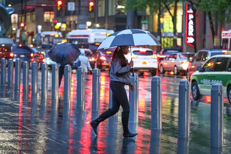 A woman runs through the rainy night at 15th and Market streets in Center City. Friday, April 26, 2019