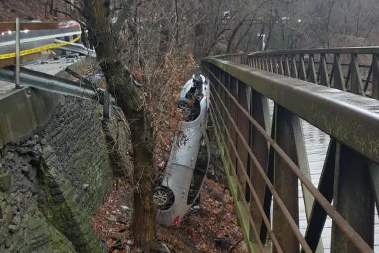 A car stands upright on the wrong side of a Lincoln Drive guard rail, leaning against an elevated section of the Wissahickon Bike Trail. Philadelphia Streets Department has touted the $12 million Lincoln Drive project as part of its increased “Vision Zero” initiative.