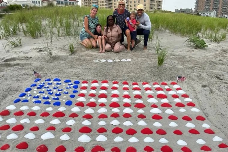 Ventnor neighbors pose with their seashell flag installation, which they arranged near the Amherst Avenue beach entrance last week. (From left to right) Susan Chihi, 39, Siena Chihi, 6, Dale Jeremiah, 57, Joanne Graham, 67, Nico Chihi, 3, and Kyce Chihi, 41.