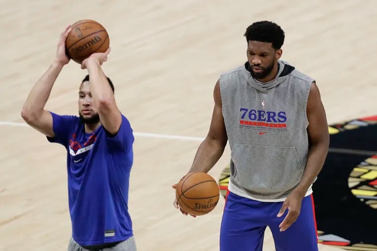 Sixers center Joel Embiid waits as teammate Ben Simmons shoots a free throw during warm-ups before a playoff game at Atlanta in June.