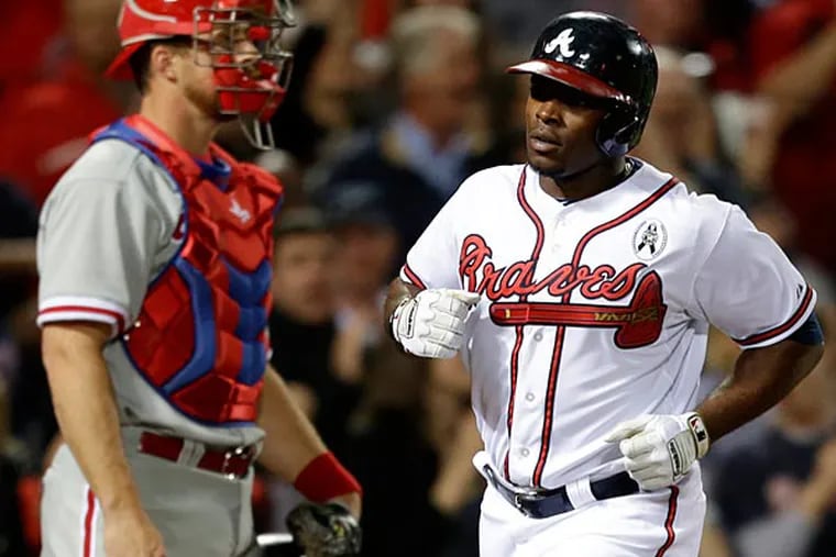 Atlanta Braves' Justin Upton, right, crosses home plate in front of Philadelphia Phillies catcher Erik Kratz after hitting a home run in the fifth inning. (AP Photo/David Goldman)
