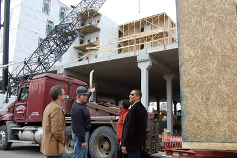 Standing near a crane that lifts 50,000-pound building modules into place at the Diamond Green Apartments complex are (from left) Jon Orens, Scott Orens, Leslie Smallwood-Lewis, and Gregory Reaves. (ALAN J. HEAVENS / Staff)
