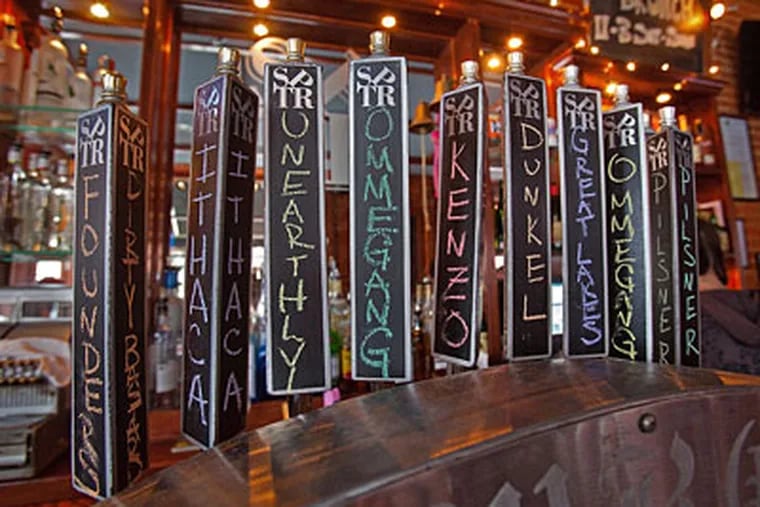 Beer taps with handwritten names at the South Philadelphia Taproom at Mifflin and South Hicks. The bar has 14 fresh taps and a 70-bottle list. (DAVID M WARREN / Staff Photographer)