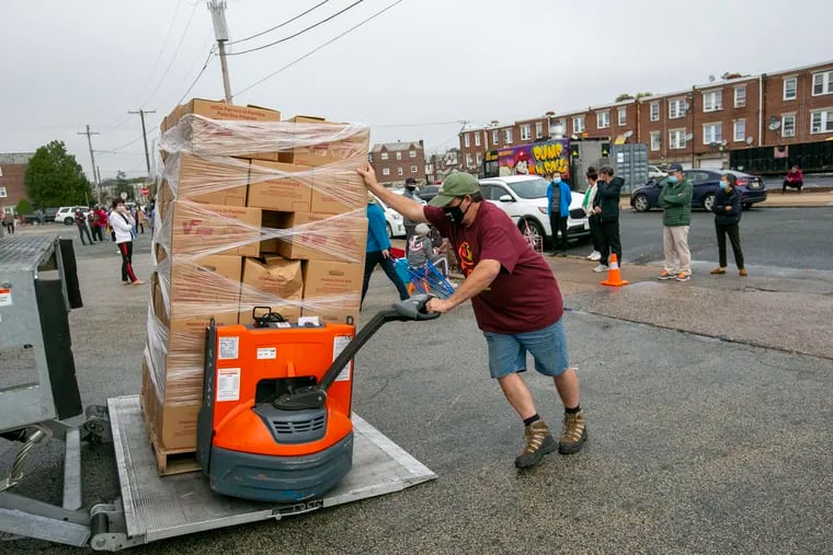 An employee with the Share Food Program in Hunting Park drops off supplies to be given away. U.S. median income declined while poverty increased in 2020.