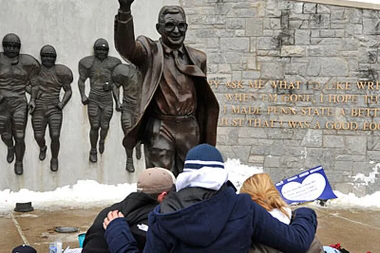 Students kneel at the foot of the Joe Paterno statue outside
of Beaver Stadium in State College. (Nabil K. Mark)