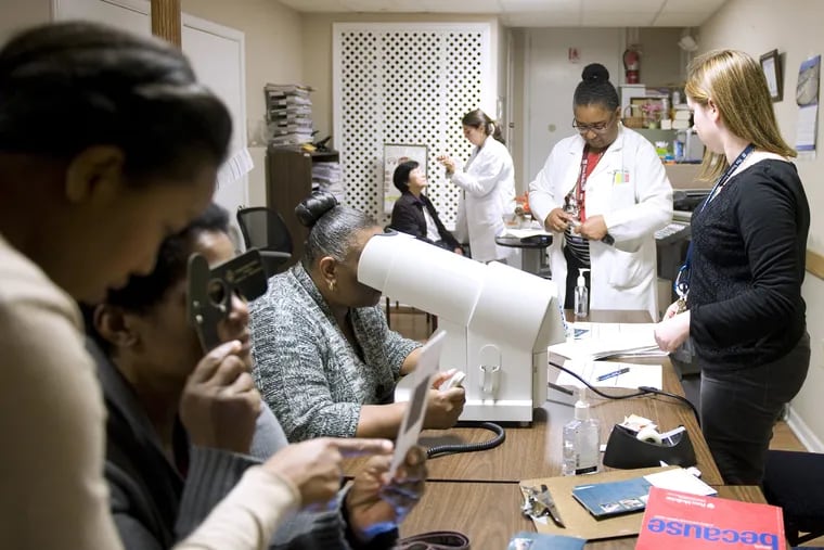 Eydie Miller-Ellis, chief of Penn Medicine's glaucoma service (end of table, in white coat) helps run a free eye screening in North Philadelphia. Some of the patients agreed to participate in a new study of genetic risk of the disease.